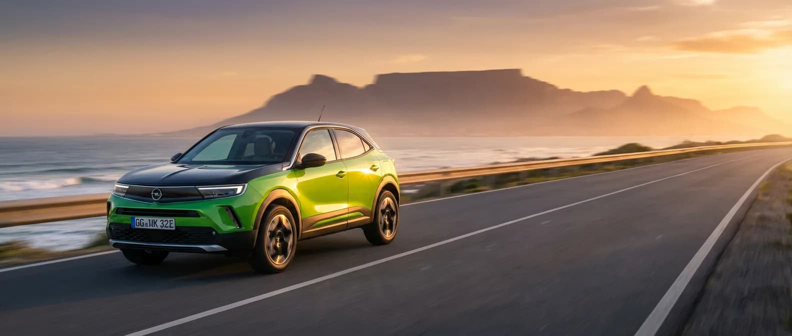 Opel Mokka électrique circulant sur une route côtière au coucher du soleil