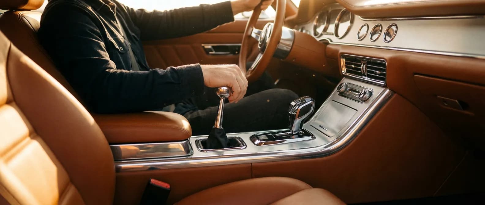 Intérieur d'une voiture haut de gamme montrant la transition entre une boîte manuelle et automatique sous une lumière cinématographique